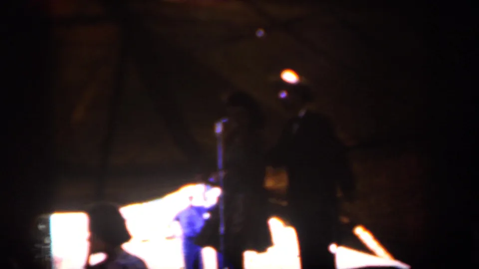 1959 Iowa 8mm view of a dim tent interior, a foreground silhouette, and a lit platform edge.
