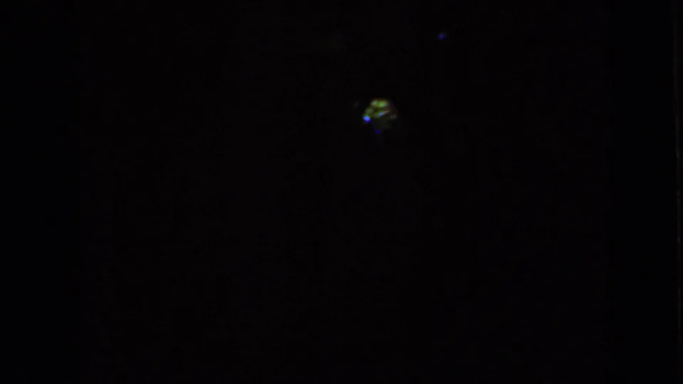 Nearly black 1959 Iowa home-movie frame with only a small colored light or reflection visible.