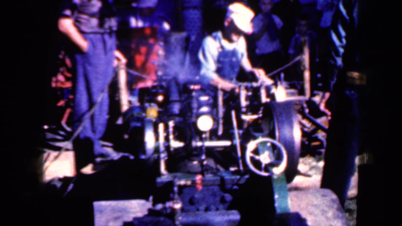 A worker in overalls appears to adjust industrial machinery in the 1959 Iowa factory scene, with vapor visible around the equipment.