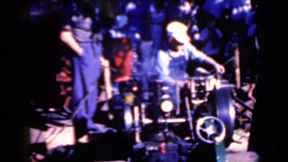 Final frame shows the operator reaching toward the log trimmer with the assistant and onlookers surrounding the work area.