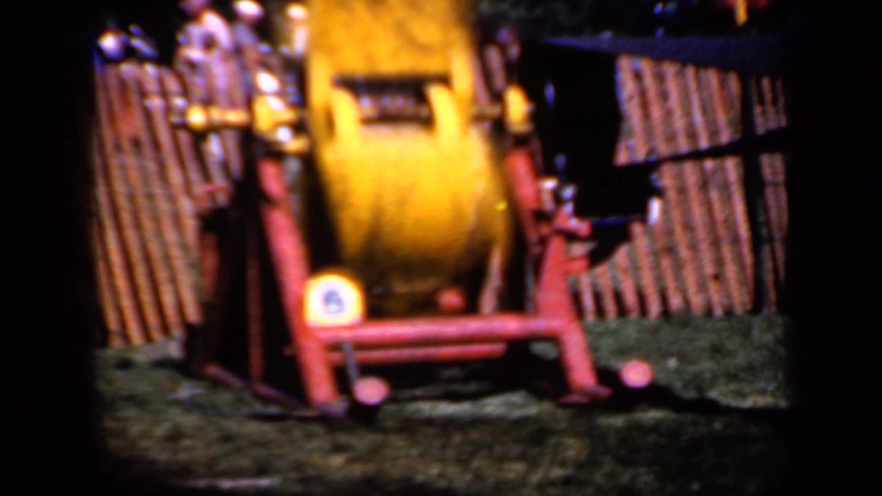 The yellow apparatus remains centered near the fence, its motion blurred in warm 8mm color.