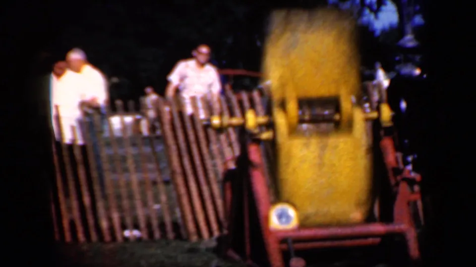 A small group of spectators remains behind the fence while the yellow industrial machine spins in the foreground.