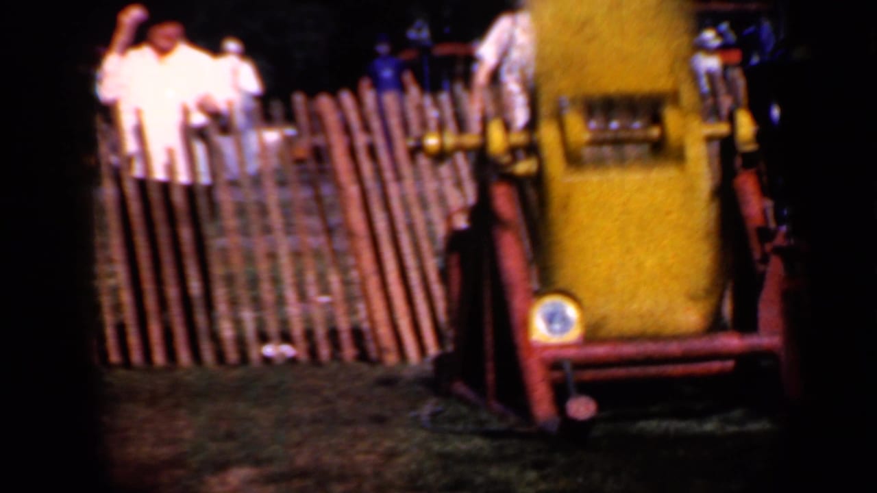 Yellow rail attraction in front of a wooden fence with two spectators behind it.