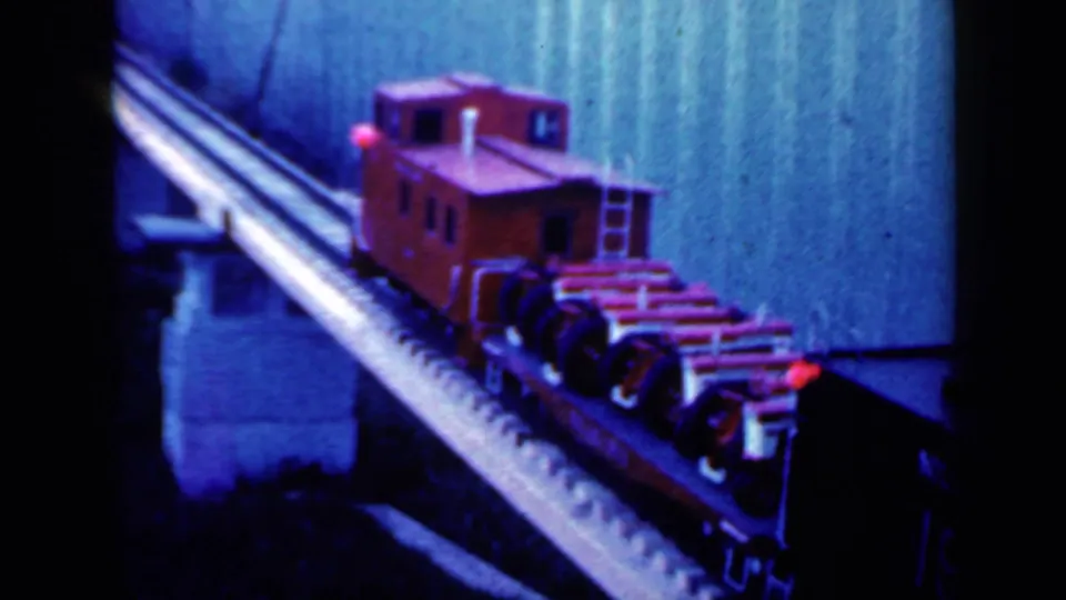 A closer 8mm view shows the red caboose on the miniature bridge, with wheel assemblies and the track structure visible.