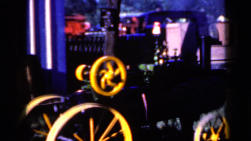 Final 1959 Iowa frame showing the small steam tractor with yellow flywheel, smoke, and other fairground tractors in the background.
