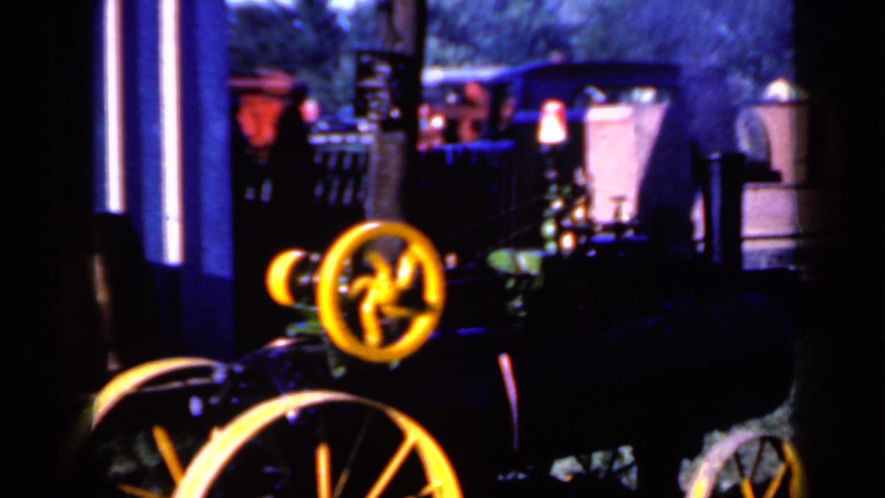 A dark 8mm frame from the Iowa clip shows yellow wheels on a vehicle or machine with blurred outdoor objects behind it.