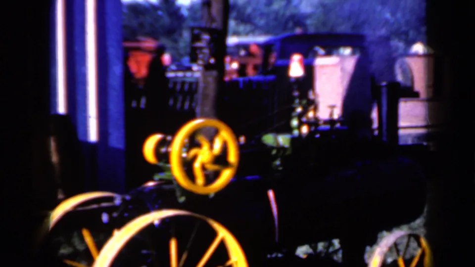 A dark 8mm frame from the Iowa clip shows yellow wheels on a vehicle or machine with blurred outdoor objects behind it.