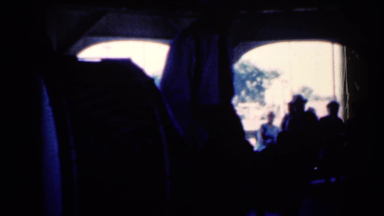 Shadowed crowd in a dark interior with a bright arched opening and a performer partly visible.