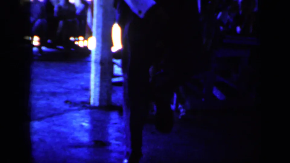Blue-tinted 1959 Iowa platform view with dark human silhouettes, bright lights, and indistinct rail-station surroundings.