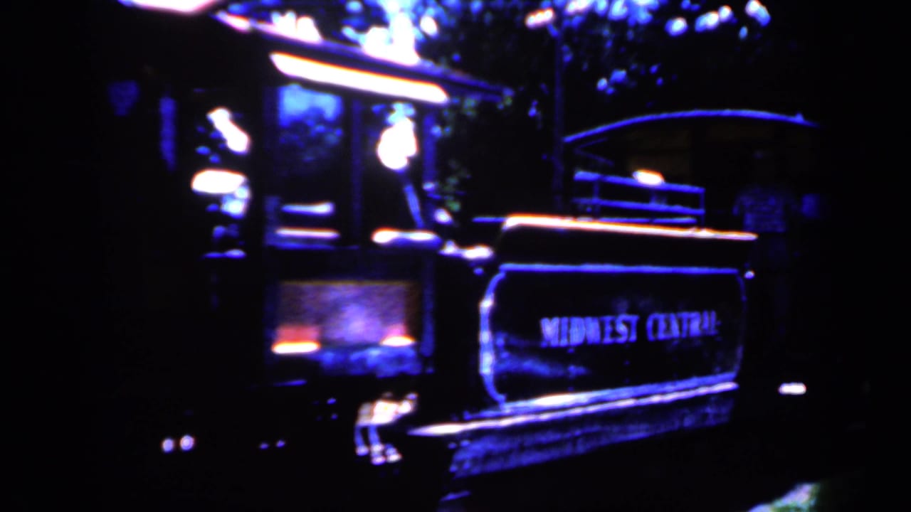Midwest Central lettering appears on a tender beside a dark locomotive in this 1959 Iowa rail scene.