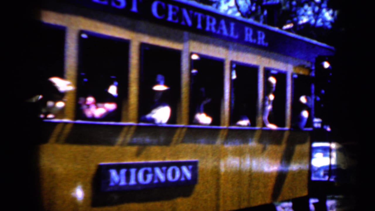 Close view of the yellow trolley side with a Mignon sign and passengers in the windows.