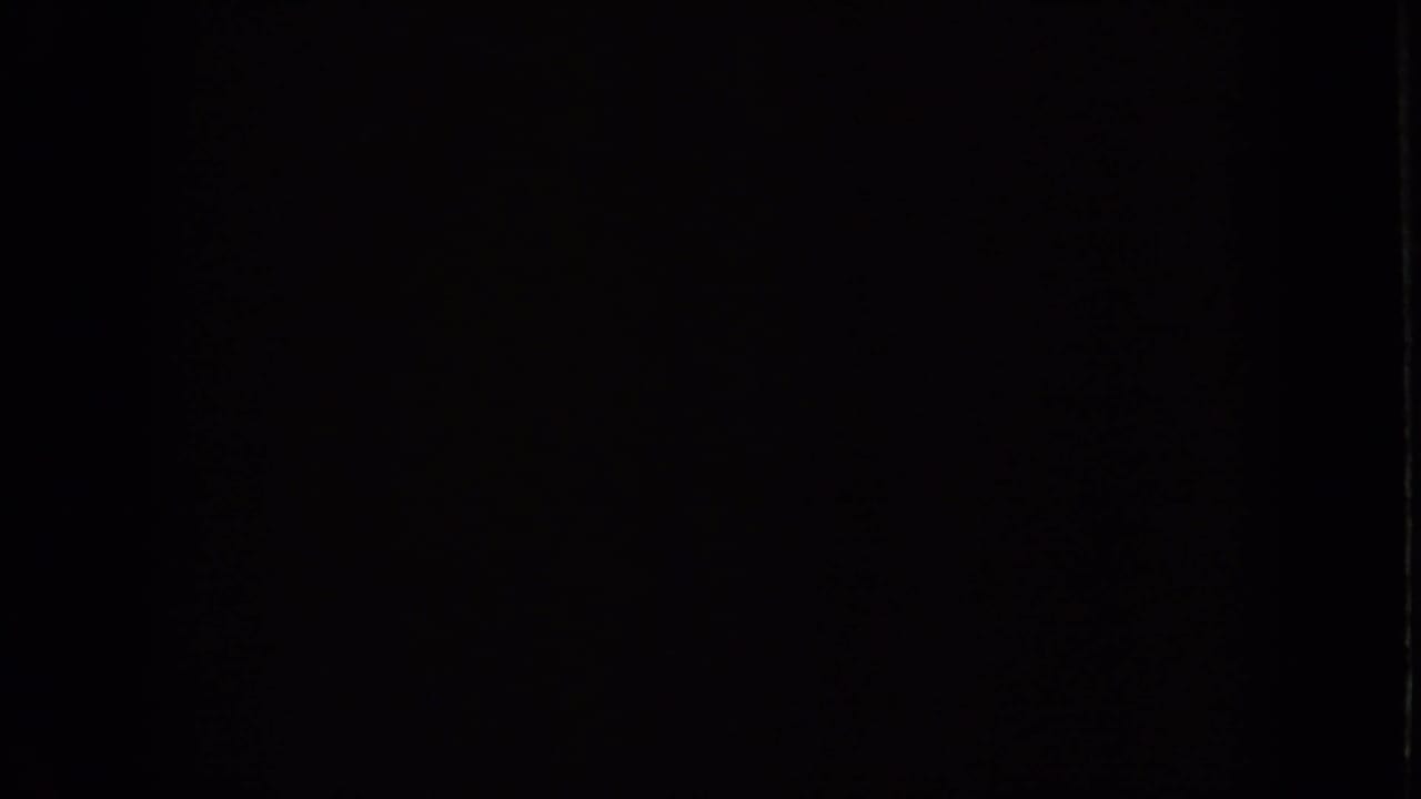 Mostly dark frame with little visible detail from the 8mm footage.