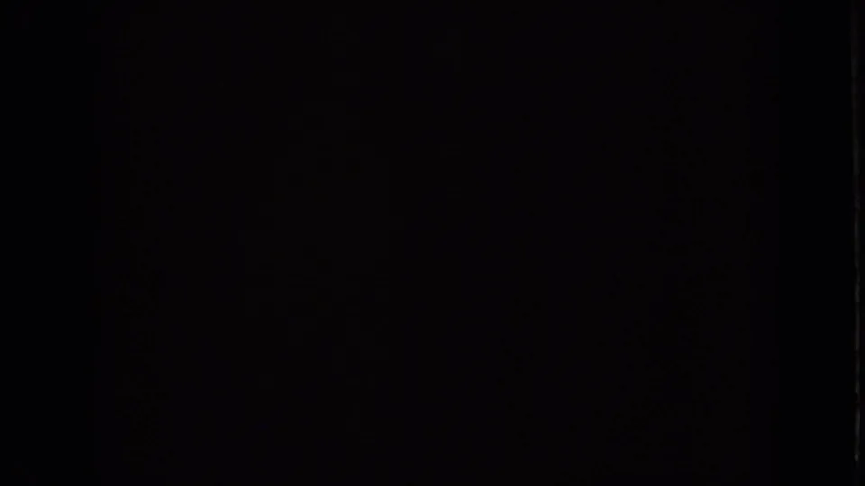 Nearly black opening frame from the Iowa 1959 home-movie clip, with only faint film texture visible.