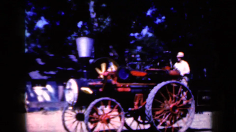 The 1959 Iowa home movie shows the steam-style vehicle passing closer to camera, with red wheels and the operator visible.