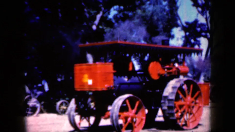 Closer 1959 Iowa view of the steam tractor, showing red spoked wheels, canopy, and steam above the engine area.