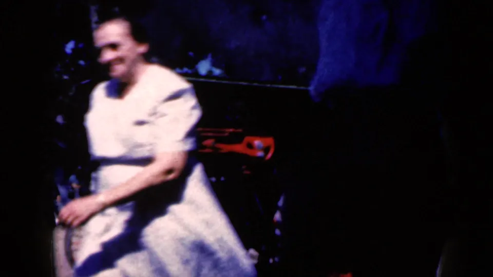An adult visitor in light-colored clothing passes close to the steam-powered vehicle, with the machinery partly obscured in shadow.