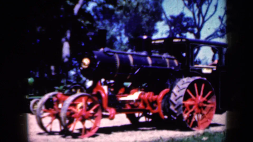 Side view of the black steam tractor with red wheels, cab and headlamp, captured as 1959 Iowa home-movie footage.
