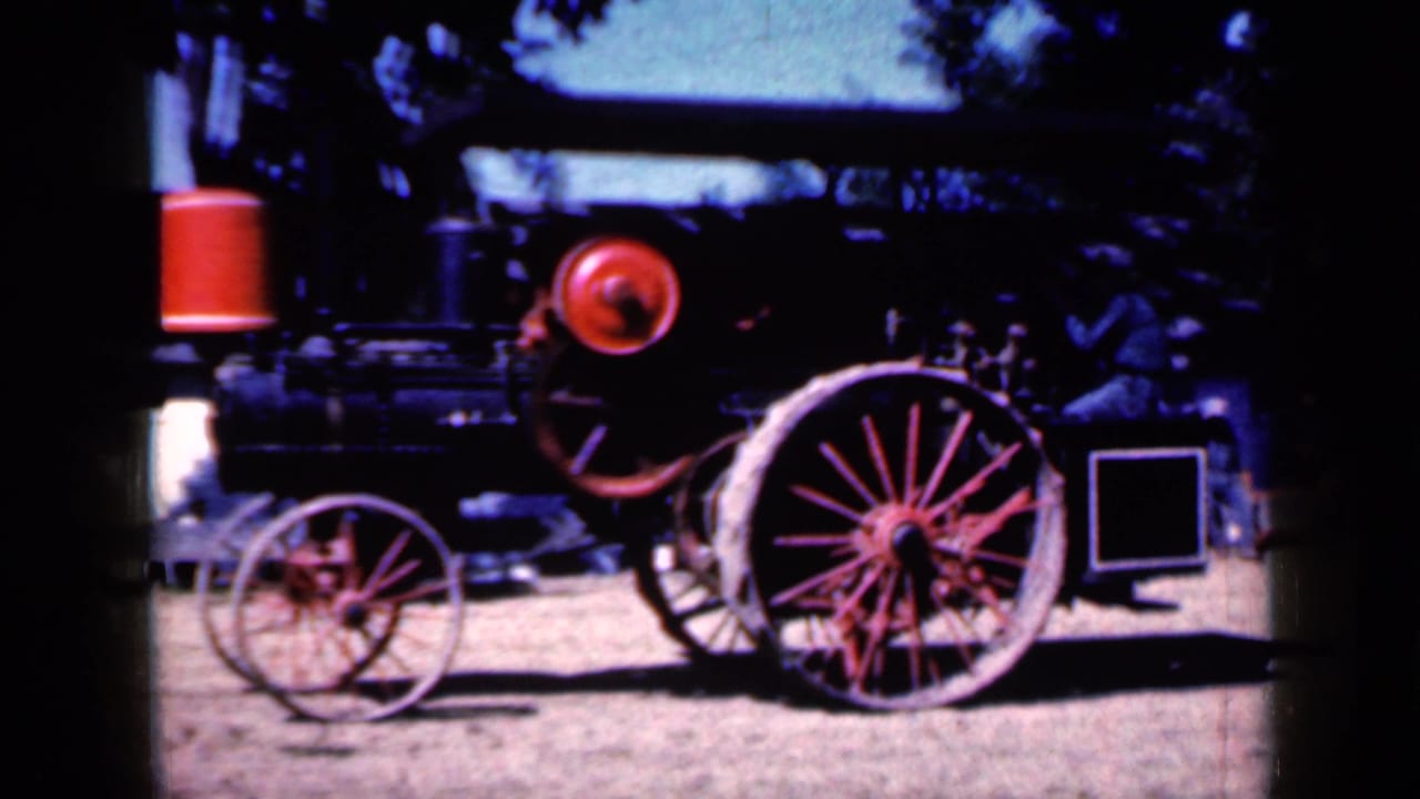 Side view of the antique steam tractor with large red rear wheel and boiler.