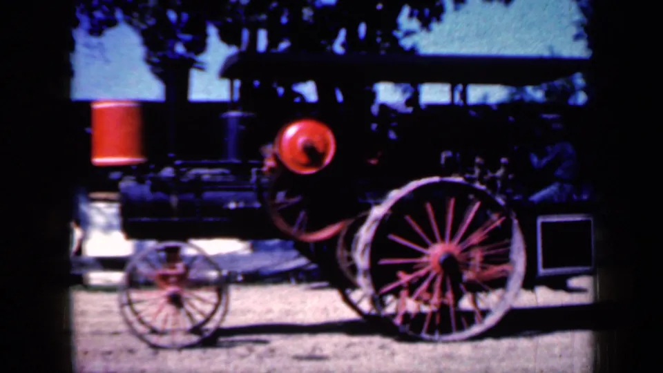 1959 Iowa 8mm frame showing a closer cropped view of the stationary steam tractor and its red wheel assembly.
