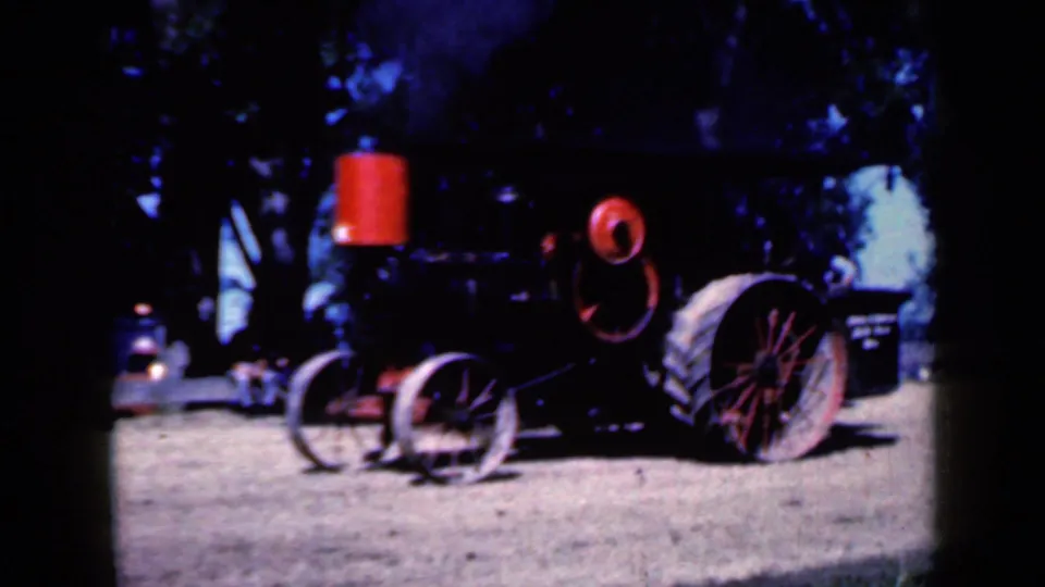 1959 Iowa 8mm frame showing the steam tractor from a rear angle, with red smokestack, red wheel, and dark boiler body.