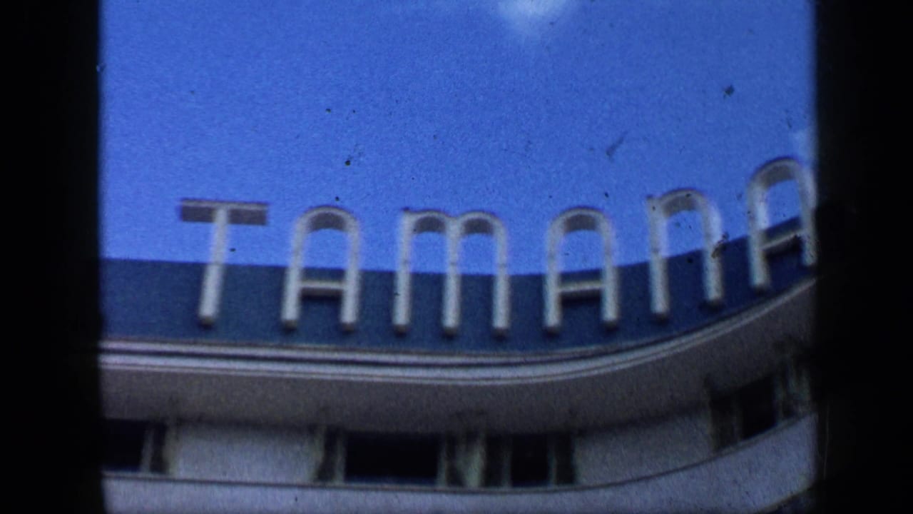 1959 Venezuela home-movie frame showing a curved exterior facade with large sign letters and blue sky.