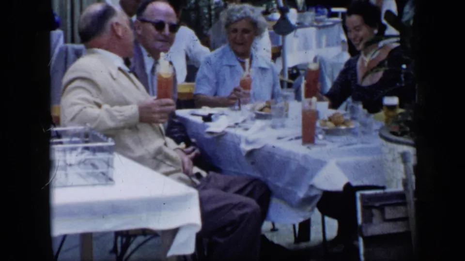 Home-movie view of adults in dressy mid-century clothing conversing at an outdoor table in Venezuela, 1959.