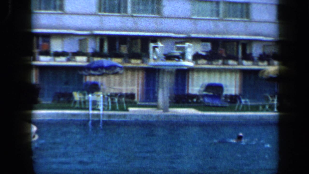 Hotel pool with a swimmer in the water and balconies above the pool deck.