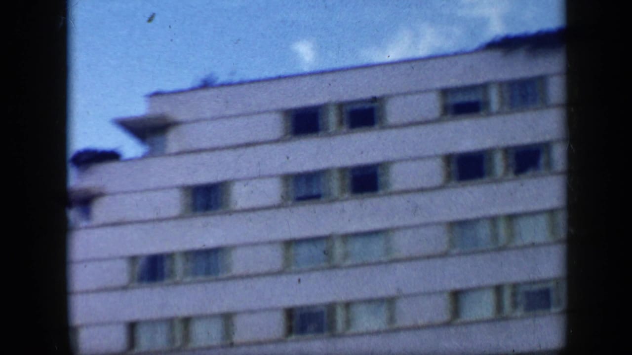 Upper floors of a white building with tiered balconies against blue sky.