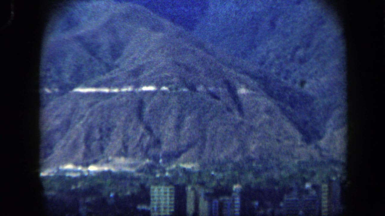 Distant mountain ridge with a cityscape at its base and a small statue on the peak.