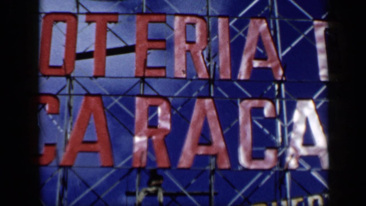 Close view of a blue Loteria de Caracas sign with red letters and scaffolding.