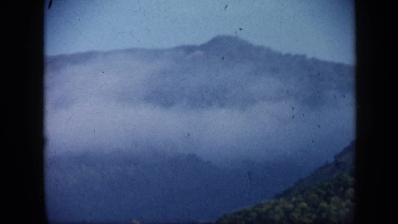 Misty mountain ridge seen through a dark 8mm film frame edge.
