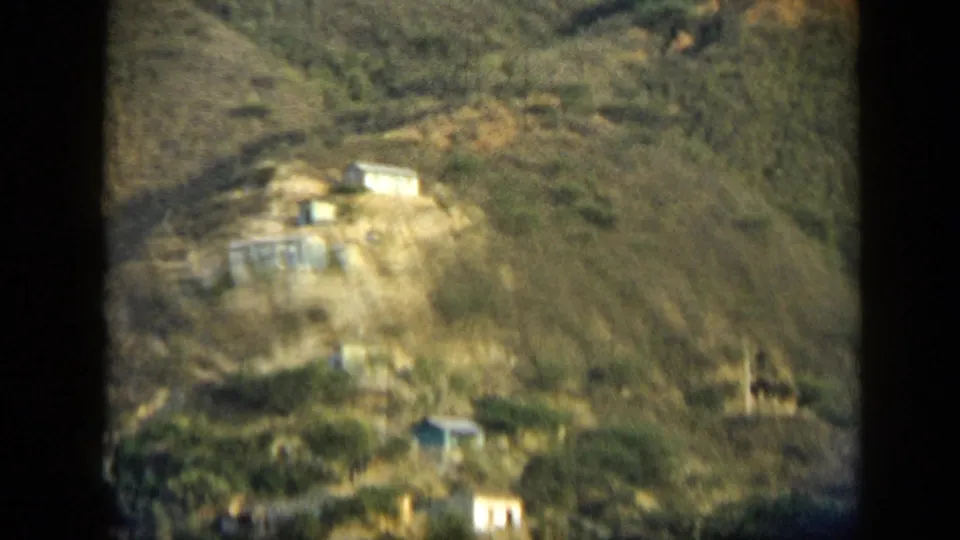 Distant hillside structures in Venezuela, filmed in 1959 with soft 8mm focus and dry mountain terrain.