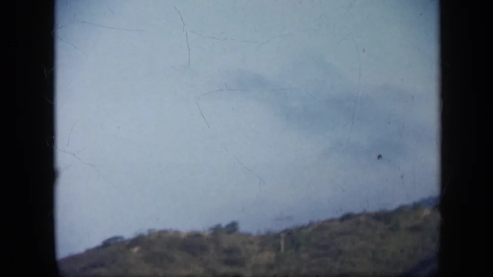 End frame from the 1959 Venezuela clip showing pale sky, a sloped ridge, and visible scratches in the 8mm scan.
