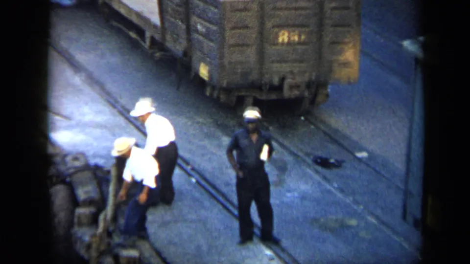 1959 Venezuela rail-yard view with workers in white and dark clothing tending freight cars and trackside equipment.