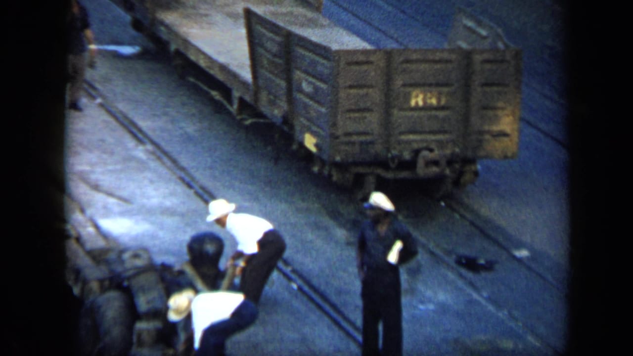 Men work near rail equipment while freight cars sit on tracks.