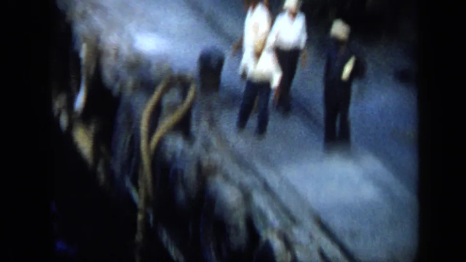 Venezuela 1959 8mm frame showing men on a dark dock near ropes or gear, softened by motion blur and low light.