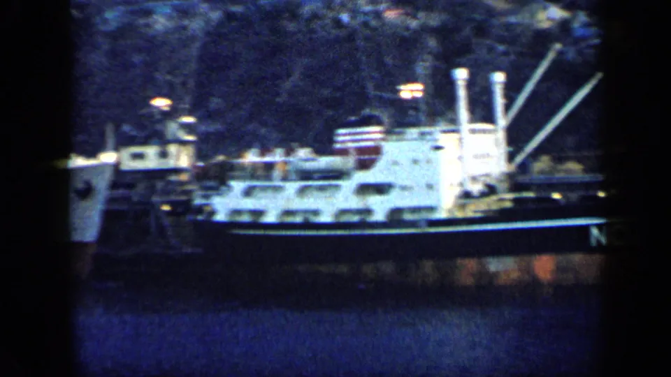 Venezuela 1959 home-movie frame showing a side view of a docked cargo ship with white superstructure and rigging.