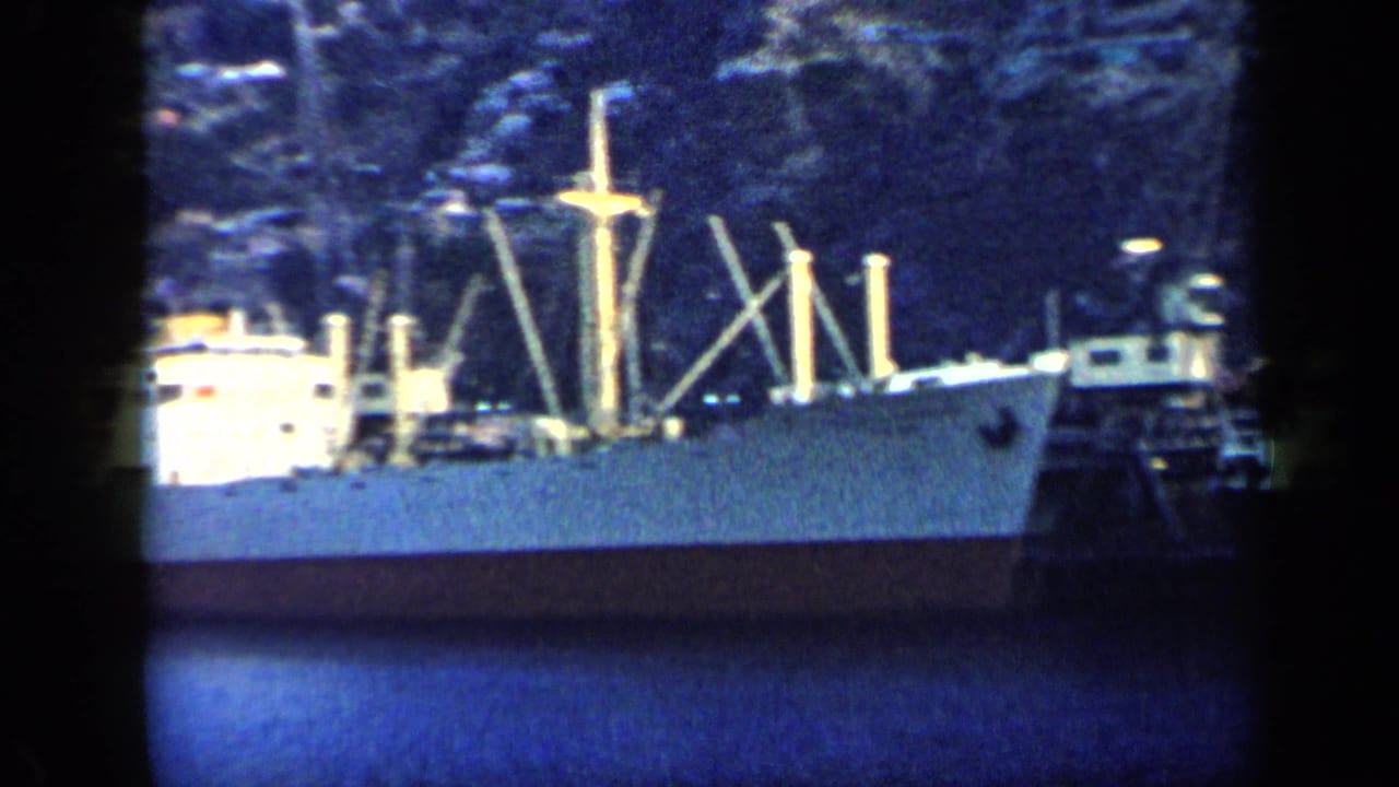 1959 Venezuela frame showing a large moored ship at night, with masts, deck structures, and dark water in the foreground.