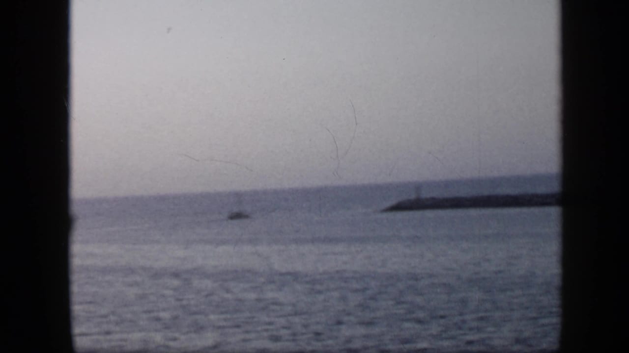 Cloudy ocean view with distant shoreline seen through dark vertical frame edges.