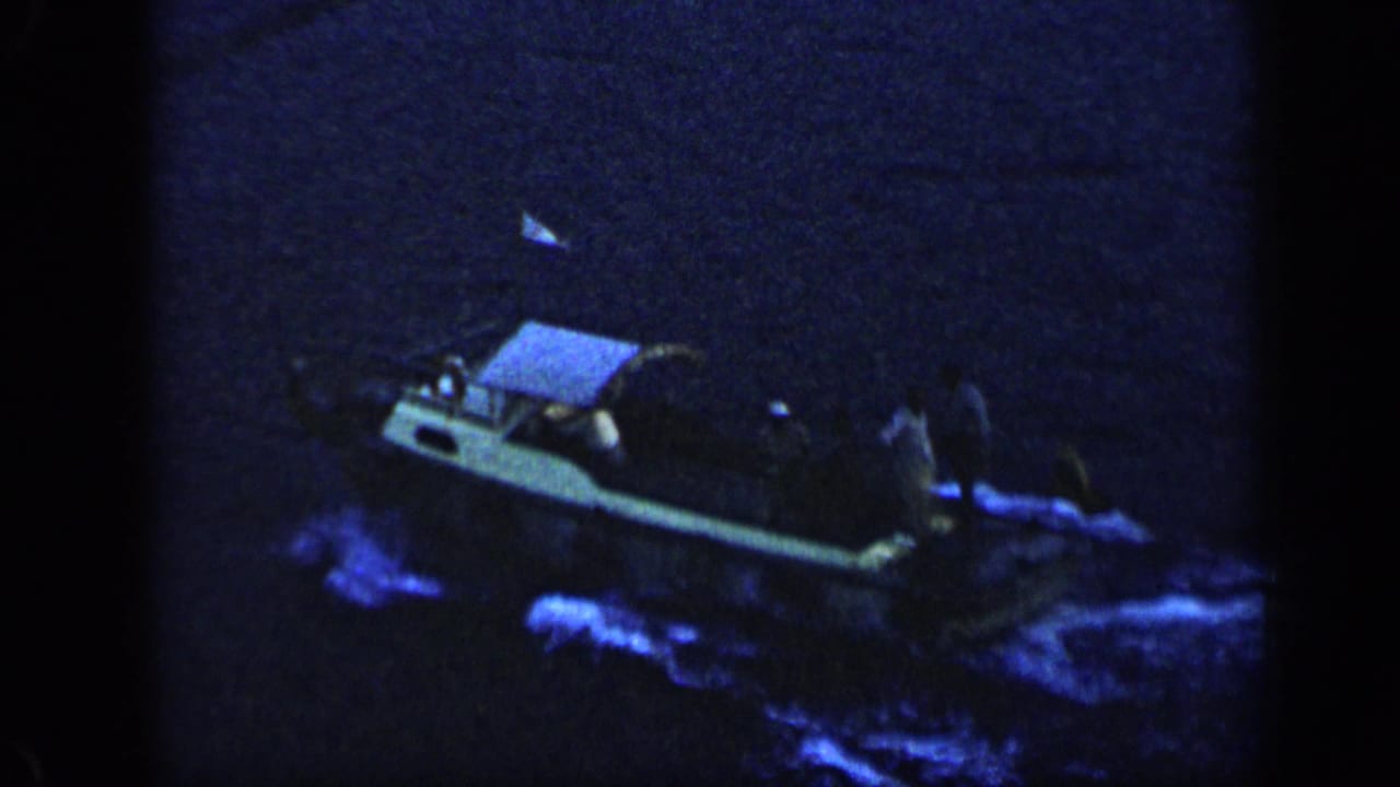 Small motorboat in Venezuela at night, its wake glowing blue as it moves across dark water.