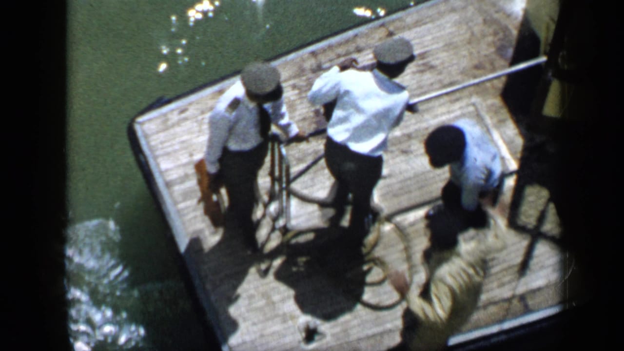 Several men stand on a wooden dock handling thick rope near the edge of the water.