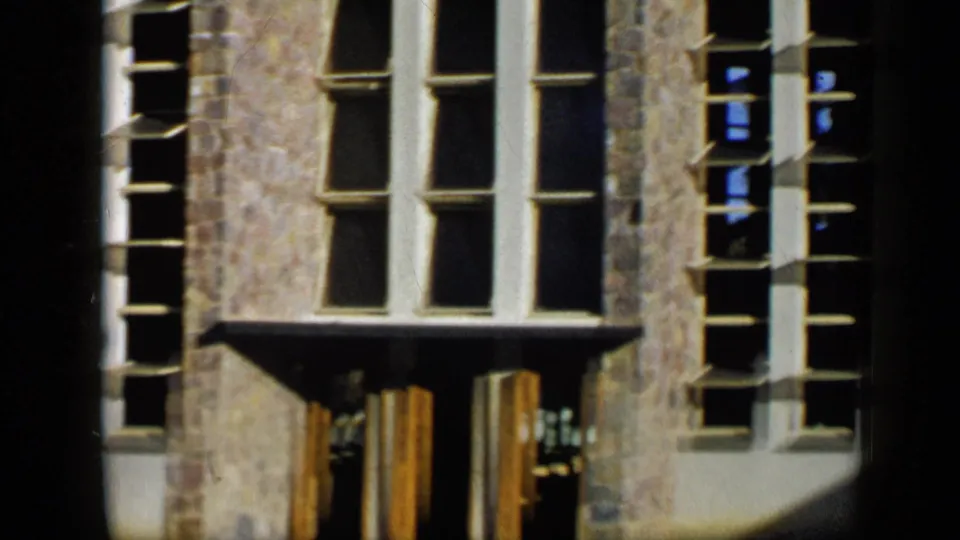 1959 Venezuela 8mm view of a stone building exterior with tall windows, a small canopy, and doorway area below.