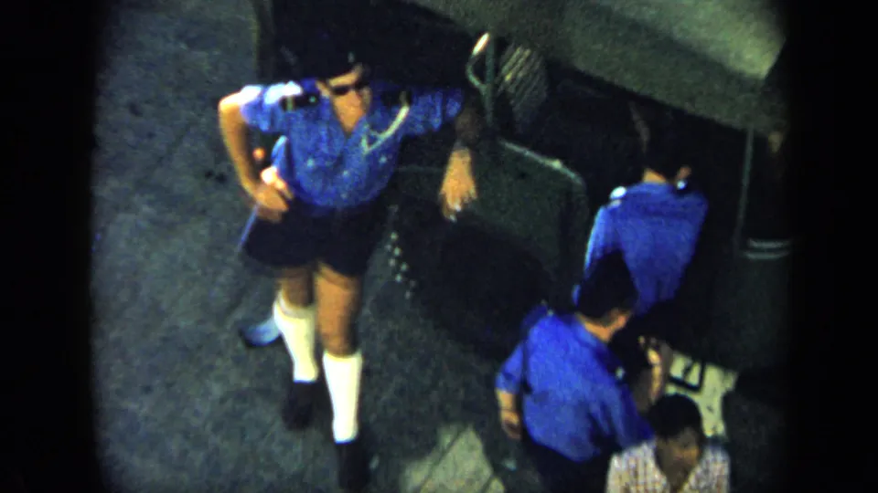 1959 Venezuela frame showing men in matching blue shirts and dark shorts on pavement, filmed from an elevated home-movie viewpoint.