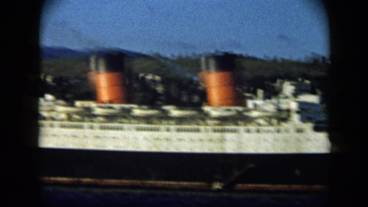 White passenger ship with two red-and-black funnels near green hills.