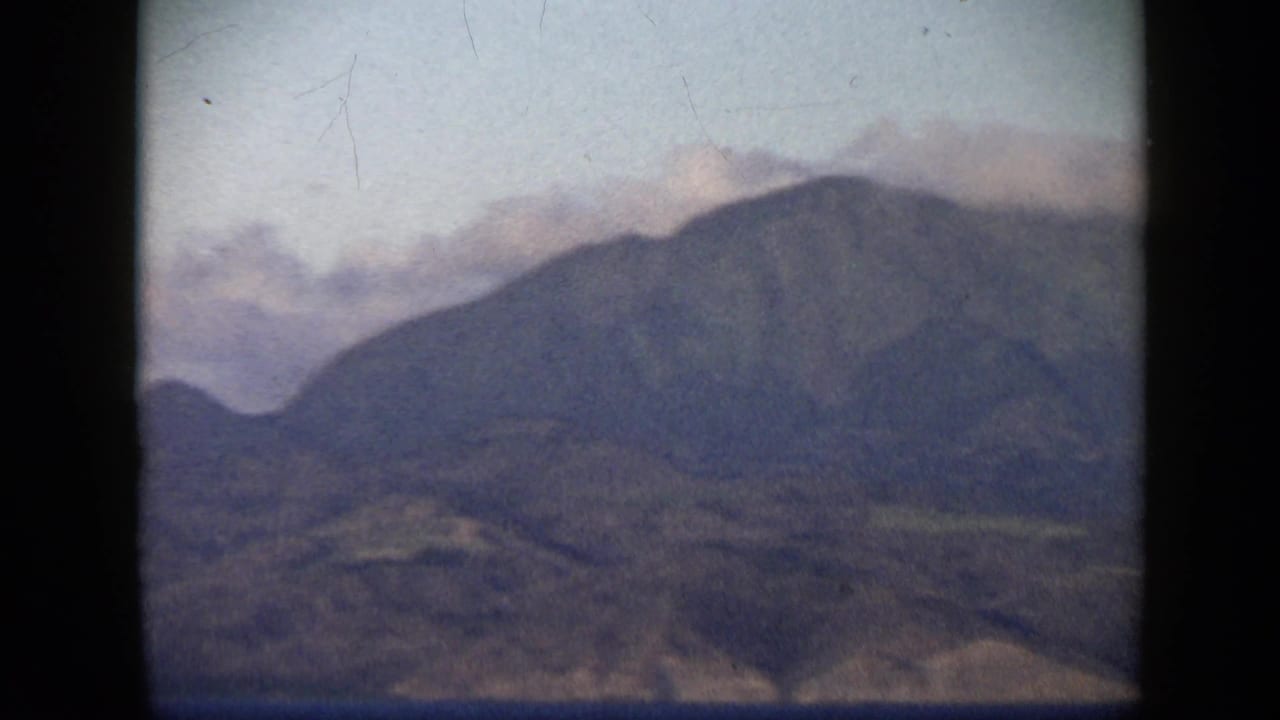 1959 Venezuela 8mm frame showing cloud brushing a mountain ridge above dry coastal terrain.