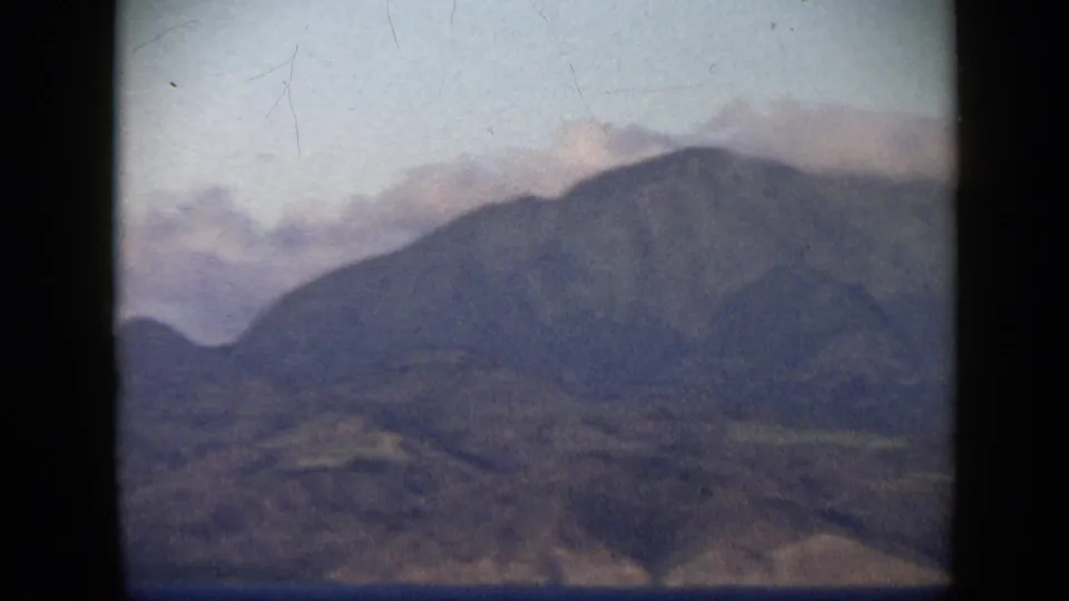 1959 Venezuela 8mm frame showing cloud brushing a mountain ridge above dry coastal terrain.