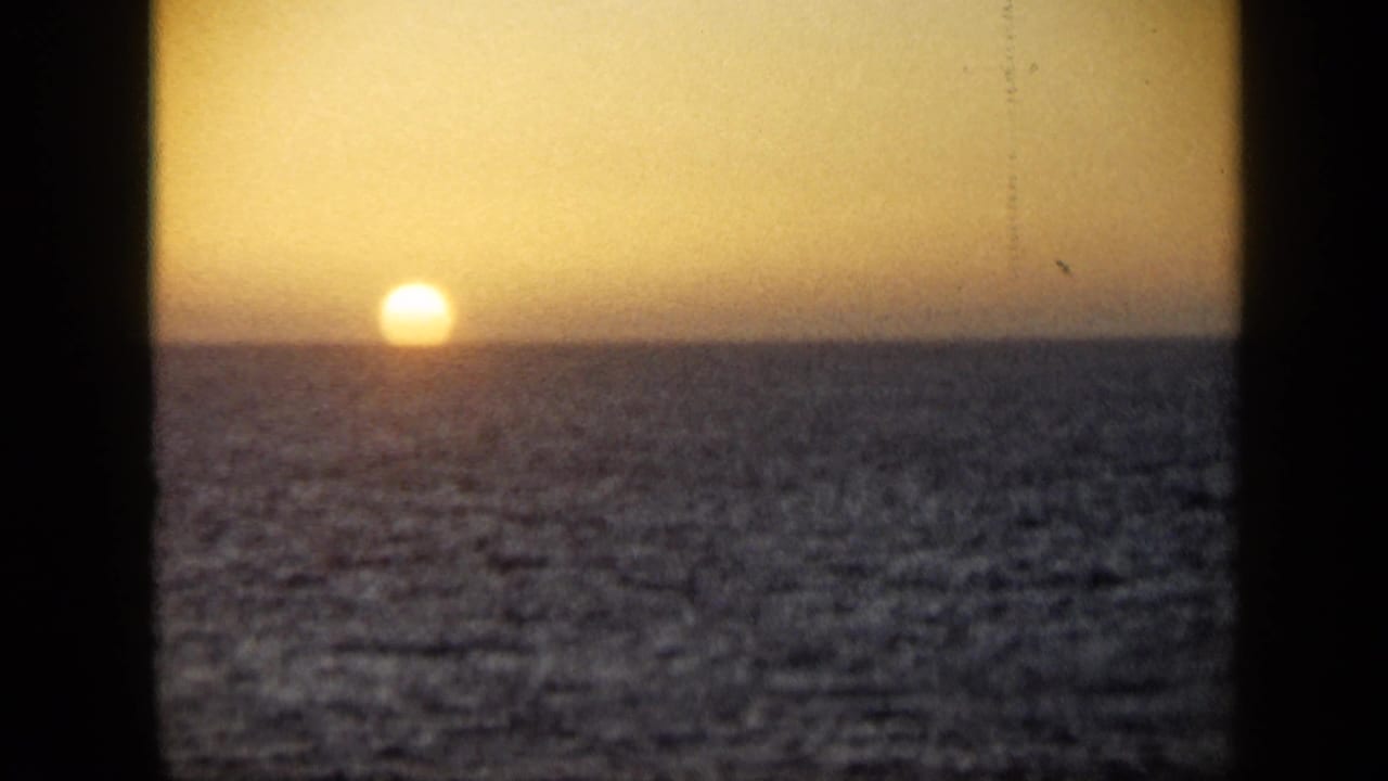 1959 Venezuela 8mm frame showing the sun at the waterline over a dark ocean and warm evening sky.