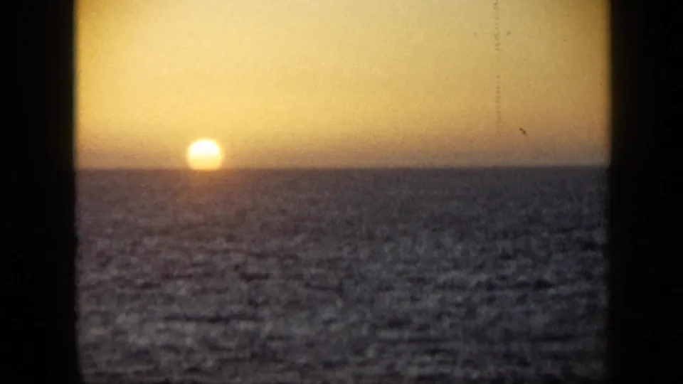 1959 Venezuela 8mm frame showing the sun at the waterline over a dark ocean and warm evening sky.