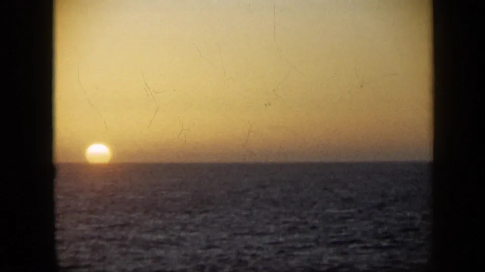 1959 Venezuela 8mm frame showing the sun low over an open ocean horizon with warm twilight color and visible film wear.