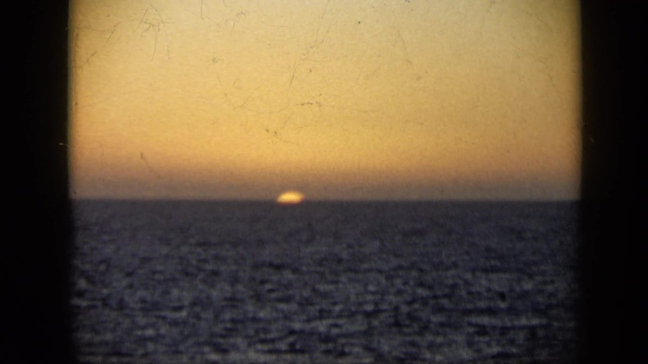 1959 Venezuela 8mm frame showing a golden sunset over open water, viewed through dark vertical framing from a boat.